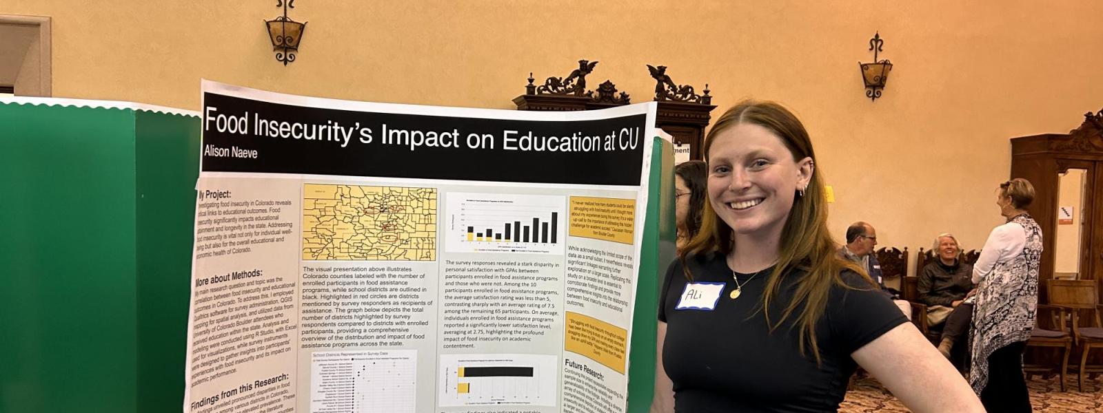 A students poses smiling next to her poster.