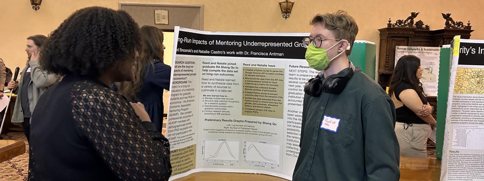 A student converses with another individual about his poster.