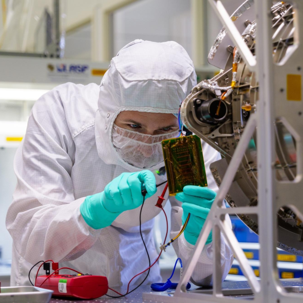 Mechanical engineer Chip Bollendonk works on the IDEX instrument in a clean room at LASP