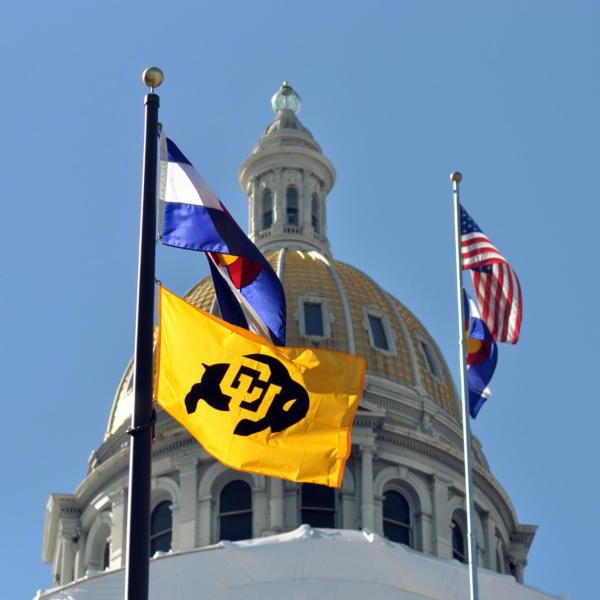CU Boulder flag flying alongside the Colorado and US flags at the Colorado State Capitol building