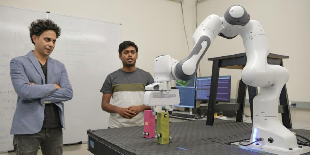 Graduate student Karan Muvvala watches as a robotic arm completes a task using wooden blocks