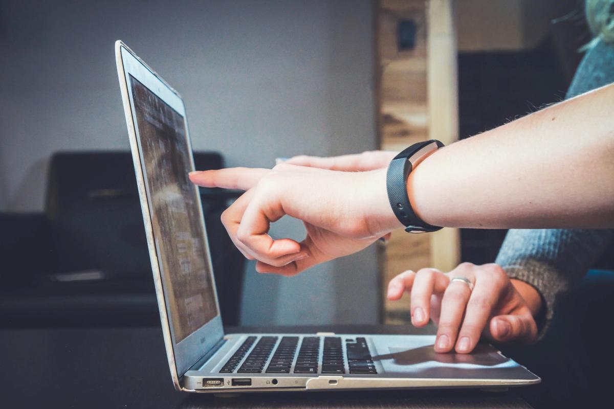 Hand pointing at a laptop screen