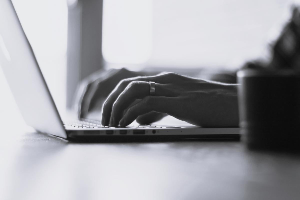 Hands typing on a laptop