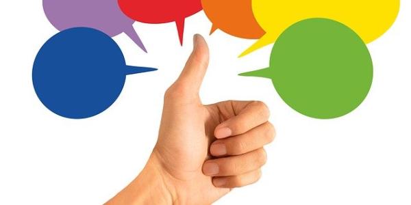 Hand showing a thumbs up with colorful speech bubbles around it.