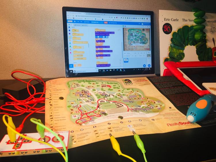 Computer screen with program code and clips attached to a paper map