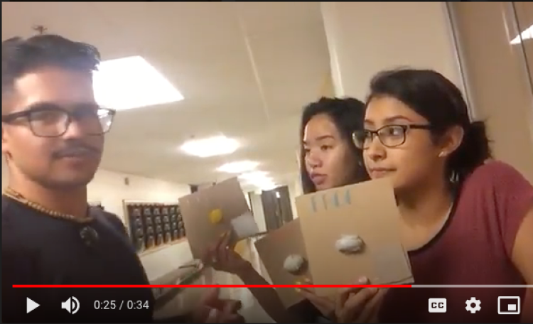 Screen shot from video of teen boy explaining project with two teen girls holding up tactile book pages.