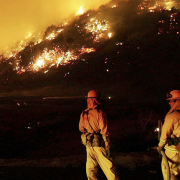 Firefighters stand in front of wildfire