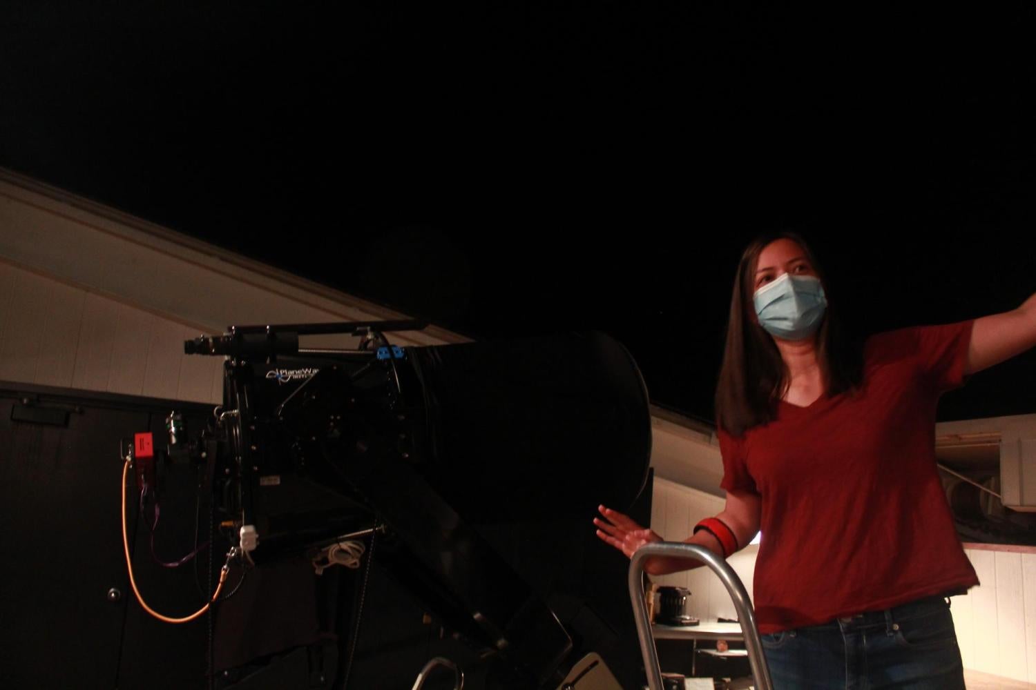 A grad student mentor on a ladder near a telescope