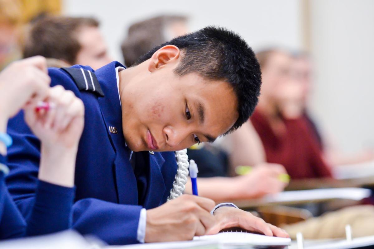 student writing on pad with pen, looking at pad