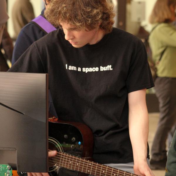 student testing guitar at tabletop activity 
