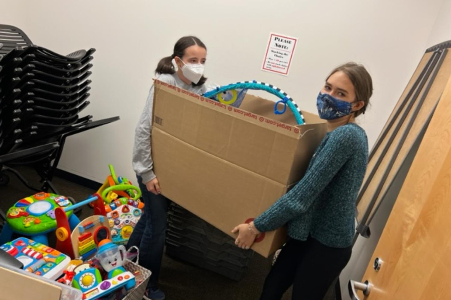 2 teens helping move a box