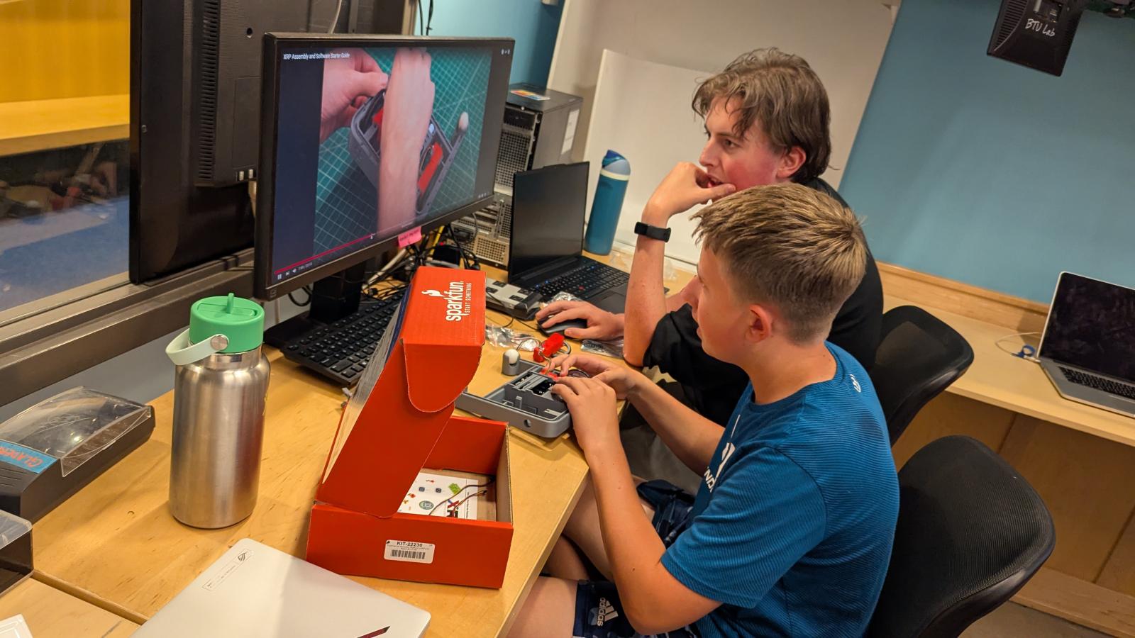 student and TA working on robotics project on computer