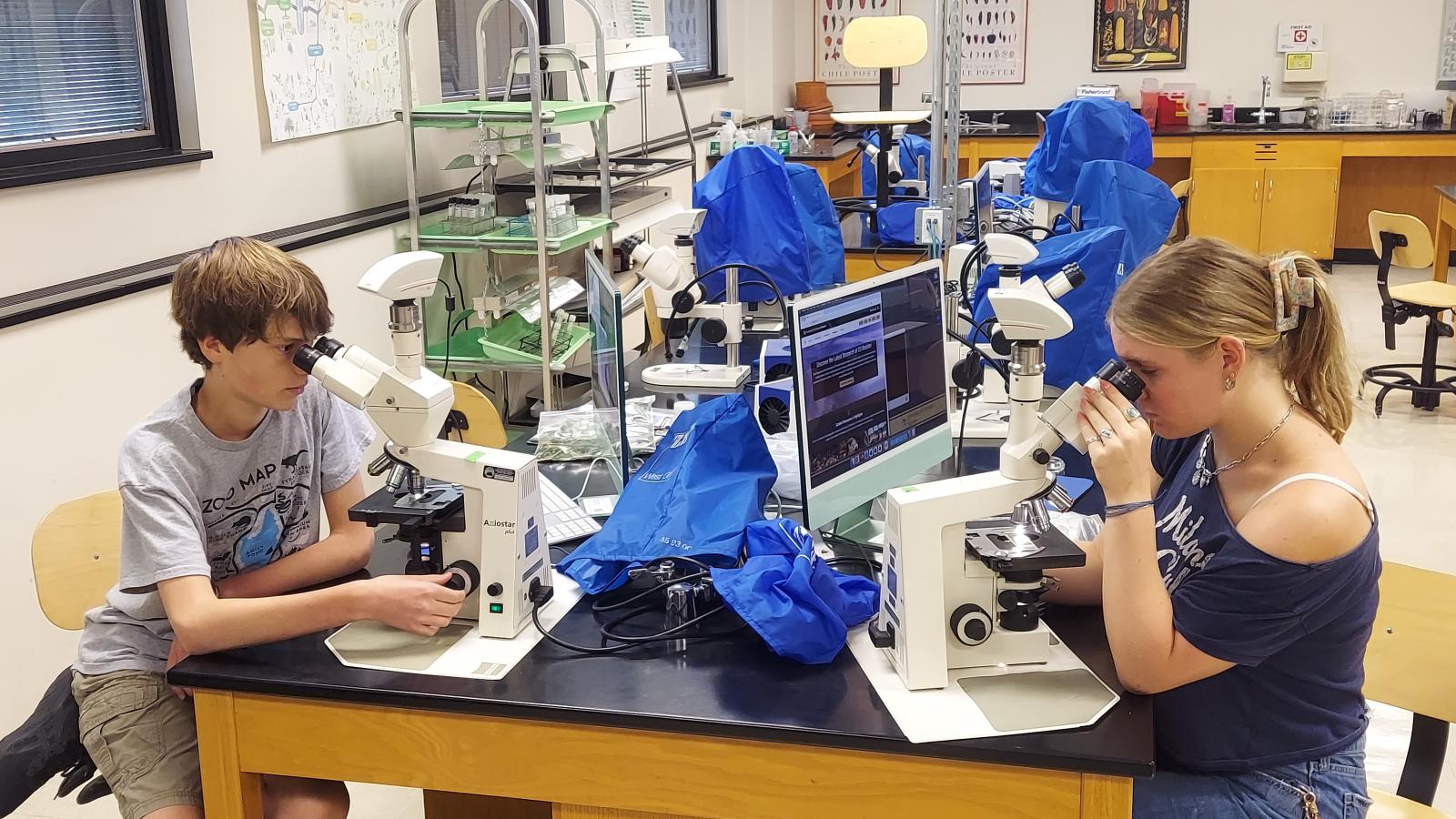two students looking into microscopes