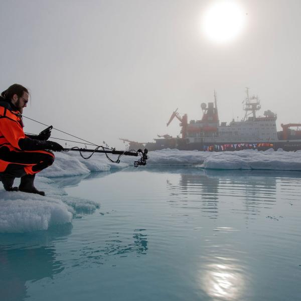 Scientist in the arctic with ship in the background