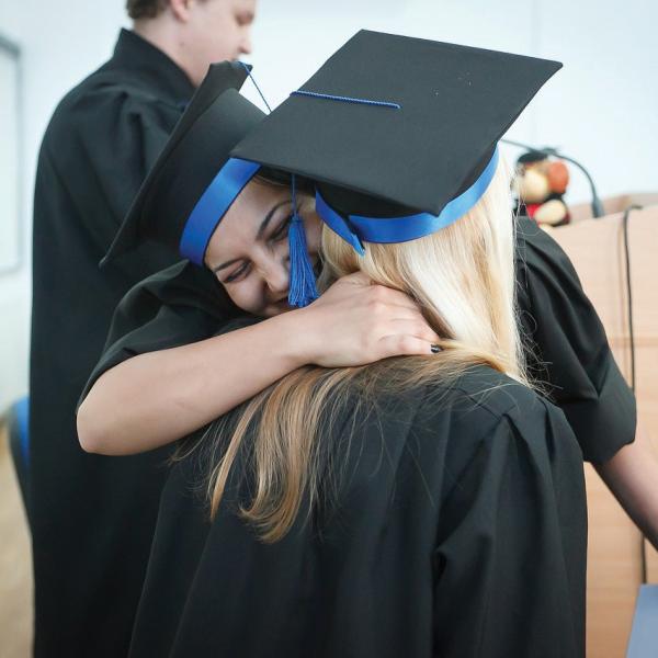 High school graduates hugging at graduation ceremony