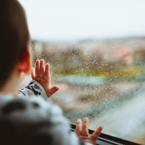 Baby touching rain spotted window