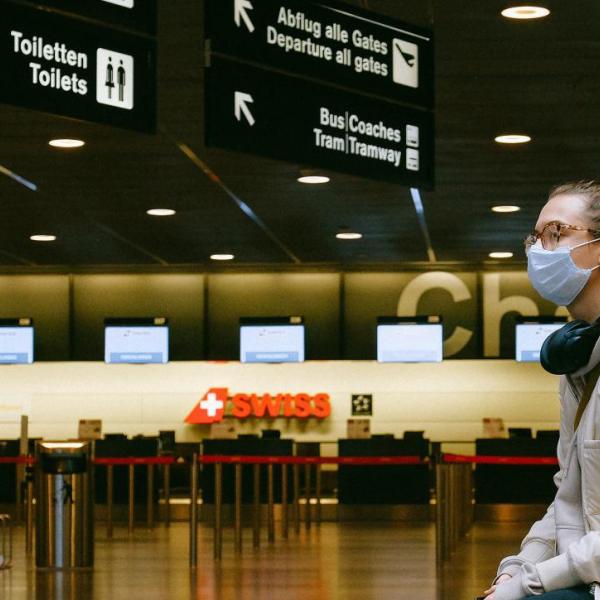 Woman sits in an airport while wearing a mask.