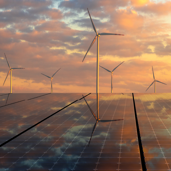 photovoltaic panels and wind turbines in the light of the rising sun