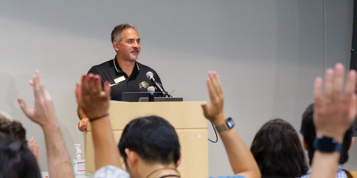 Faculty members raising hands during an address by Chancellor Justin Schwartz 