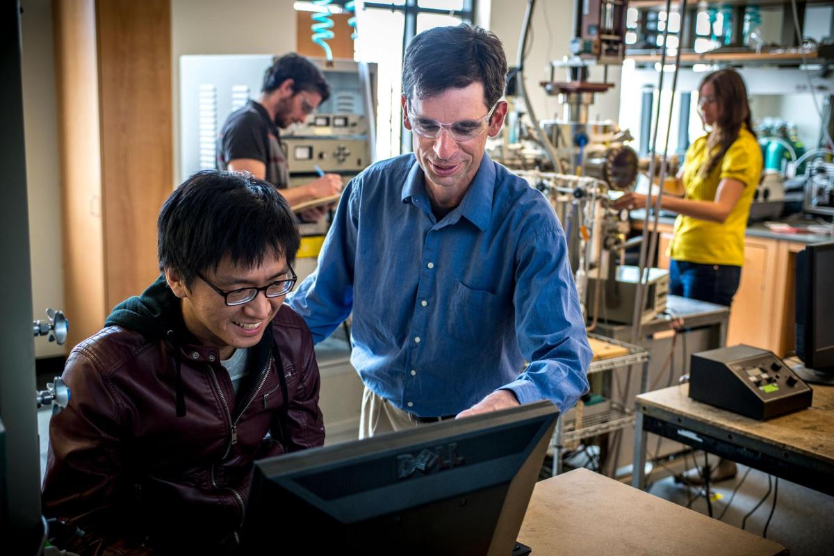 Professor helping student on laptop