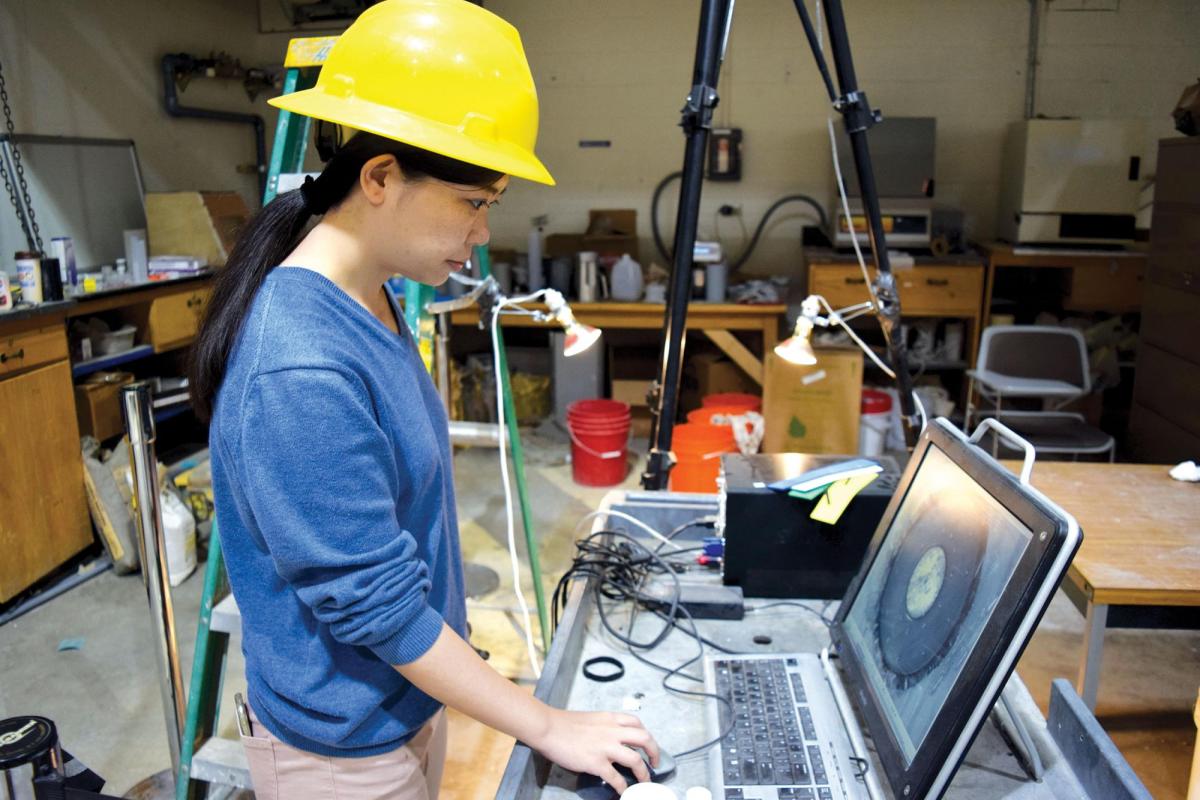 Student with hard hat working on laptop in lab