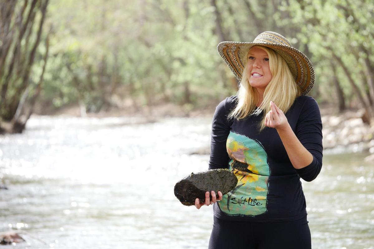 Student holding rock by stream