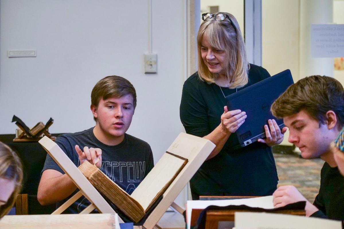 Professor with students looking at history books