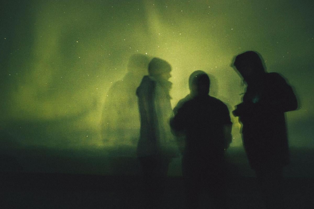 Silhouettes of people in front of green lights