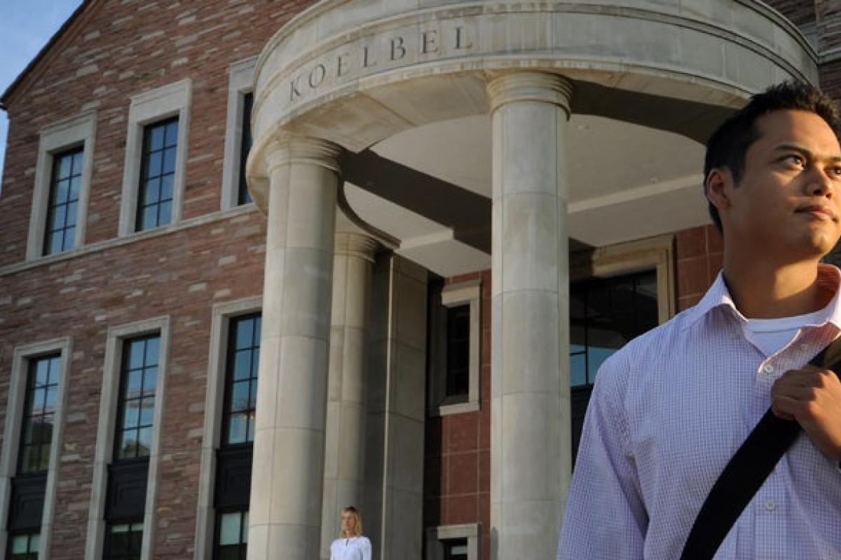 Student standing in front of Koelbel business building