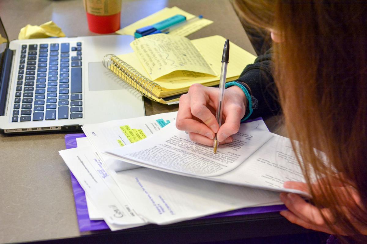 Person writing and laptop