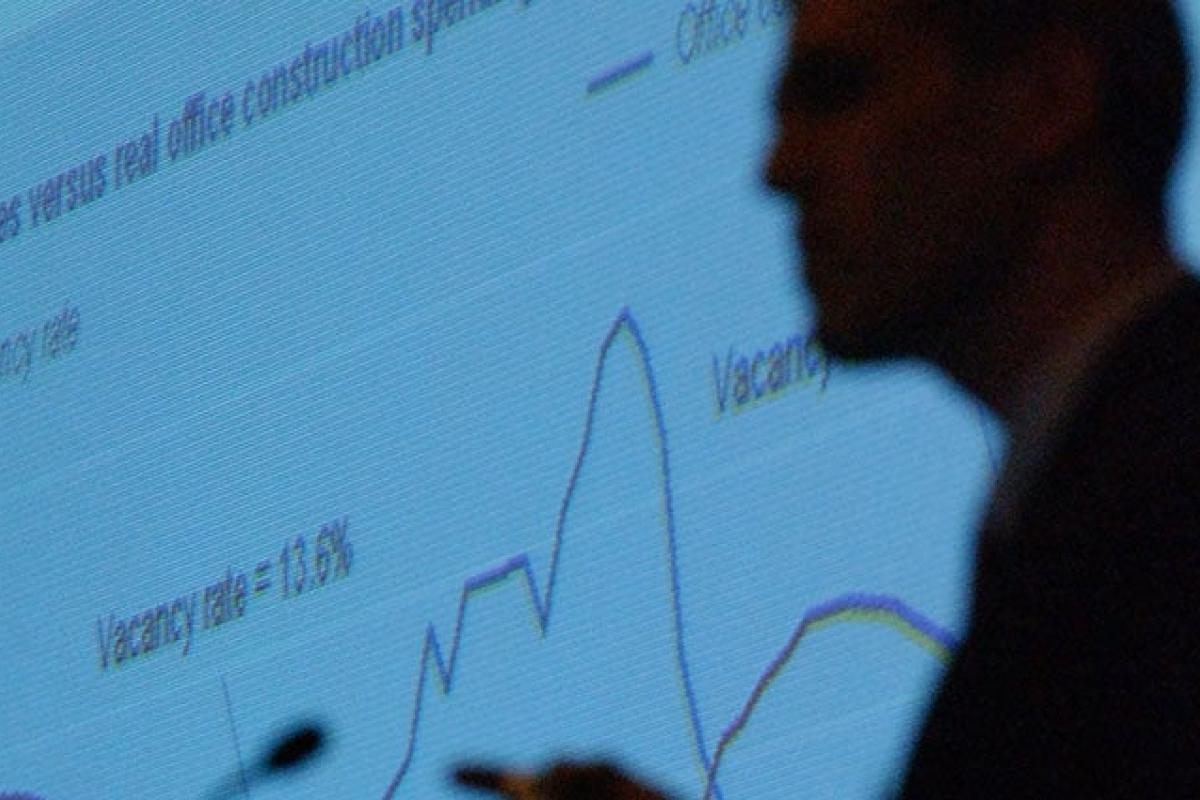 Silhouette of person giving a business and economics presentation on a screen