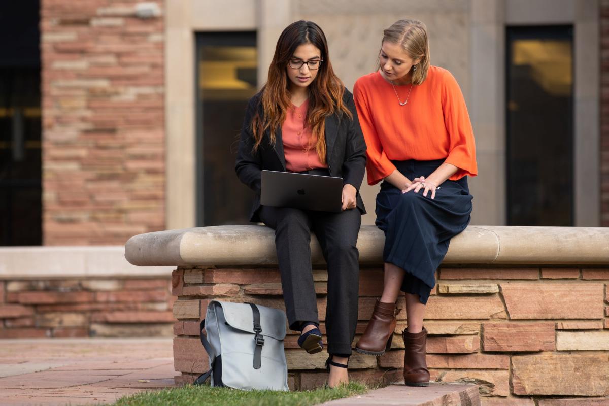 Students sitting on campus wall and studying