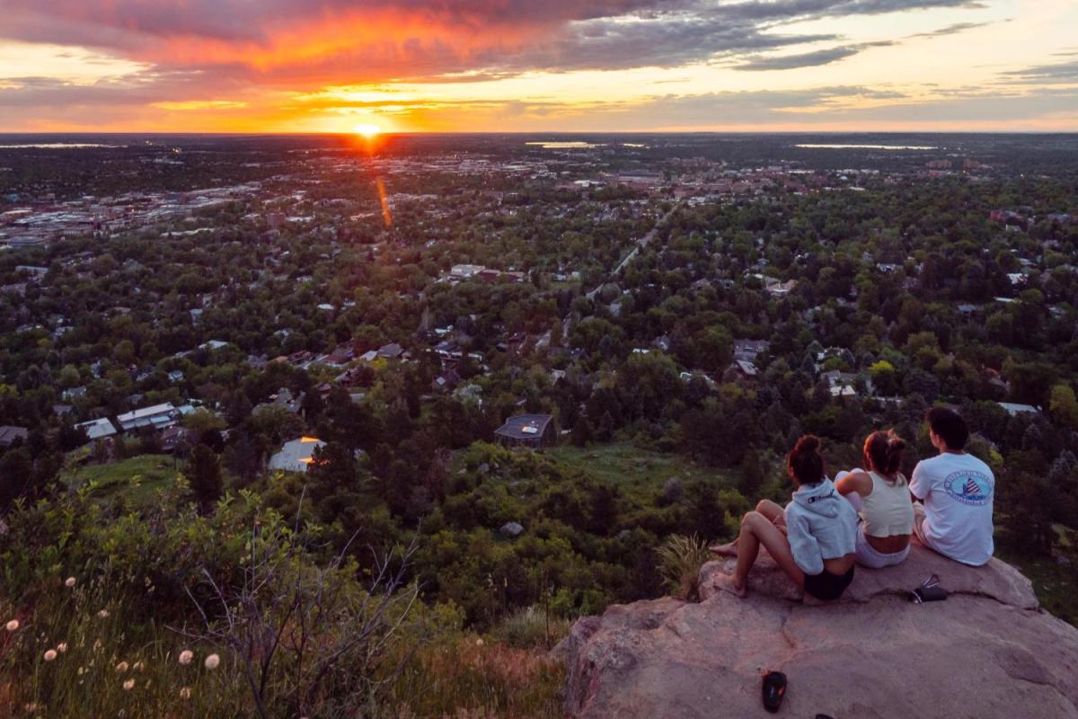 Students sitting on the Flatirons looking over Boulder at sunrise