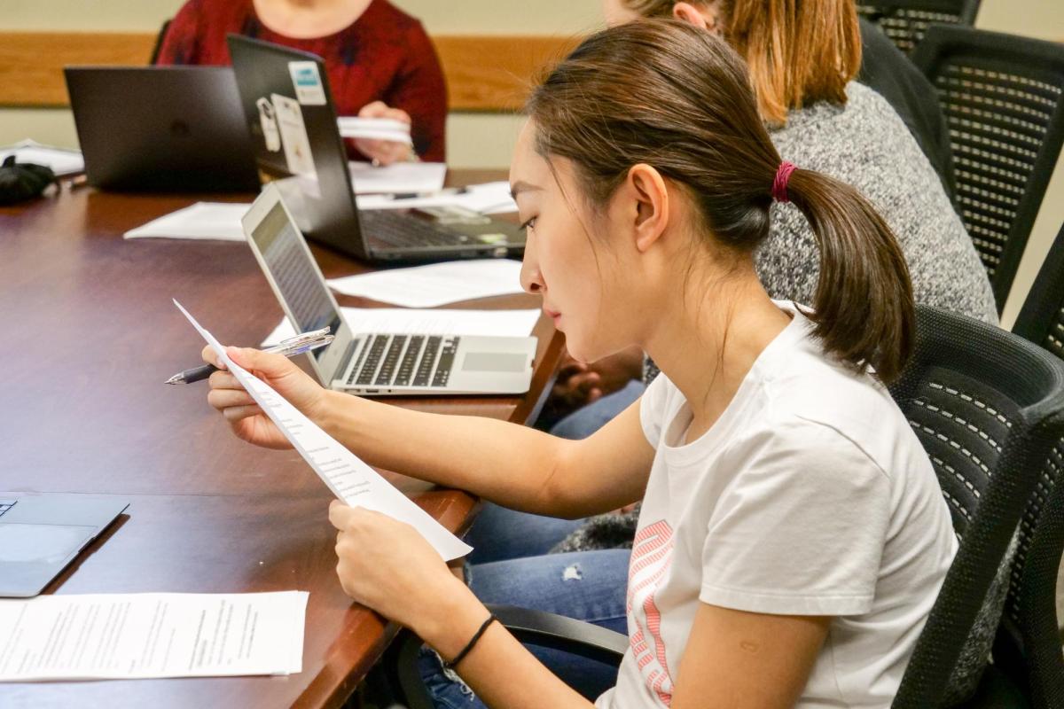Students at table reading and on laptops