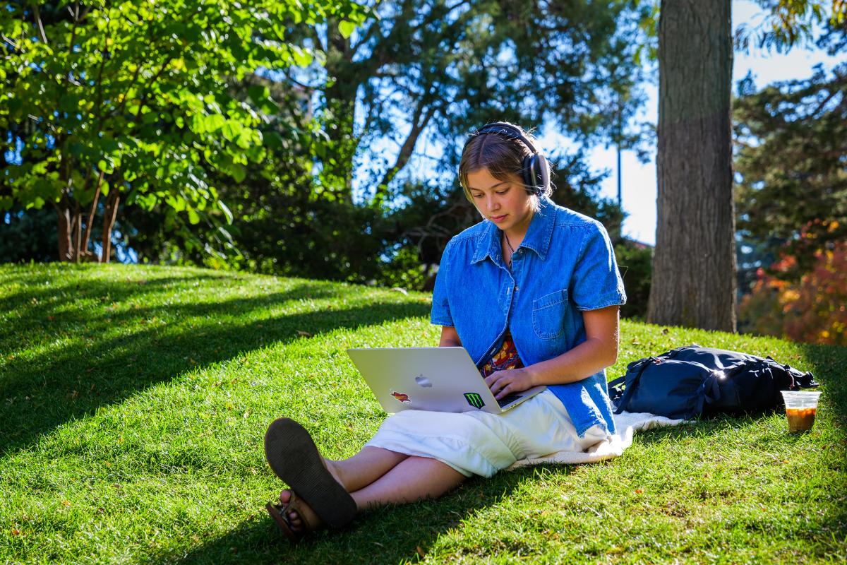 Girl working on her laptop outside during a nice fall day