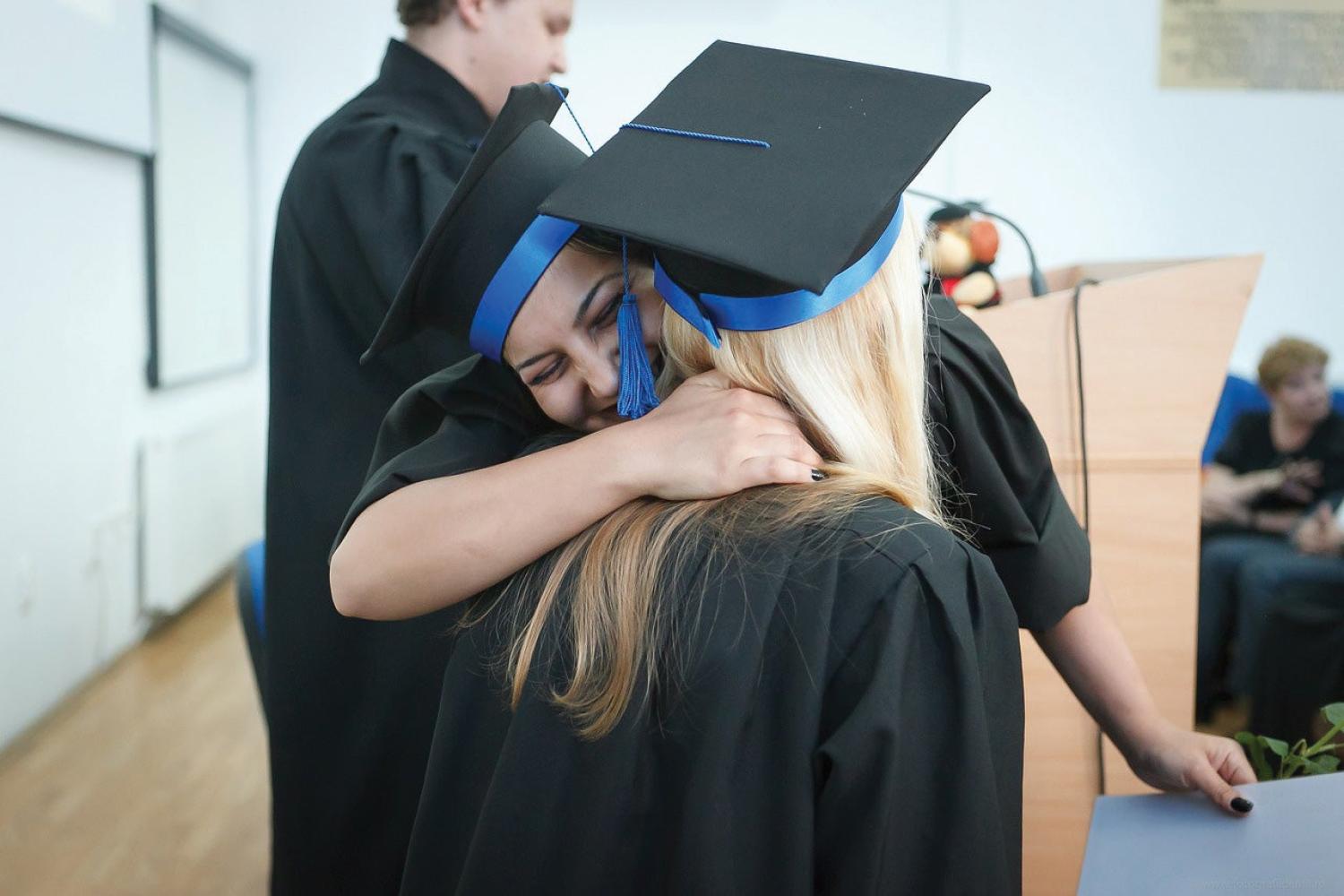 High school graduates hugging at graduation ceremony