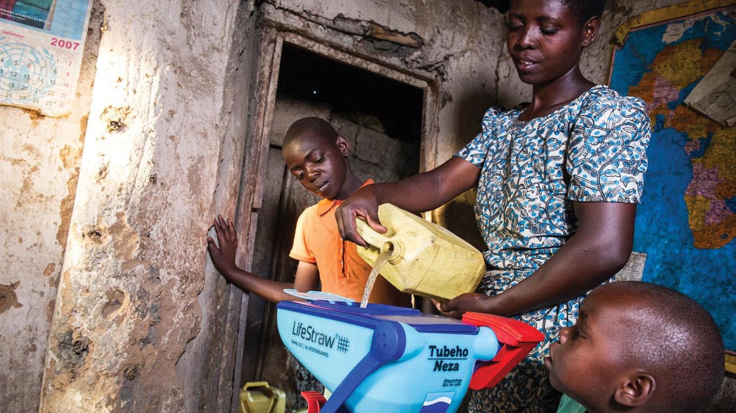 Rwandan pouring water into water filter
