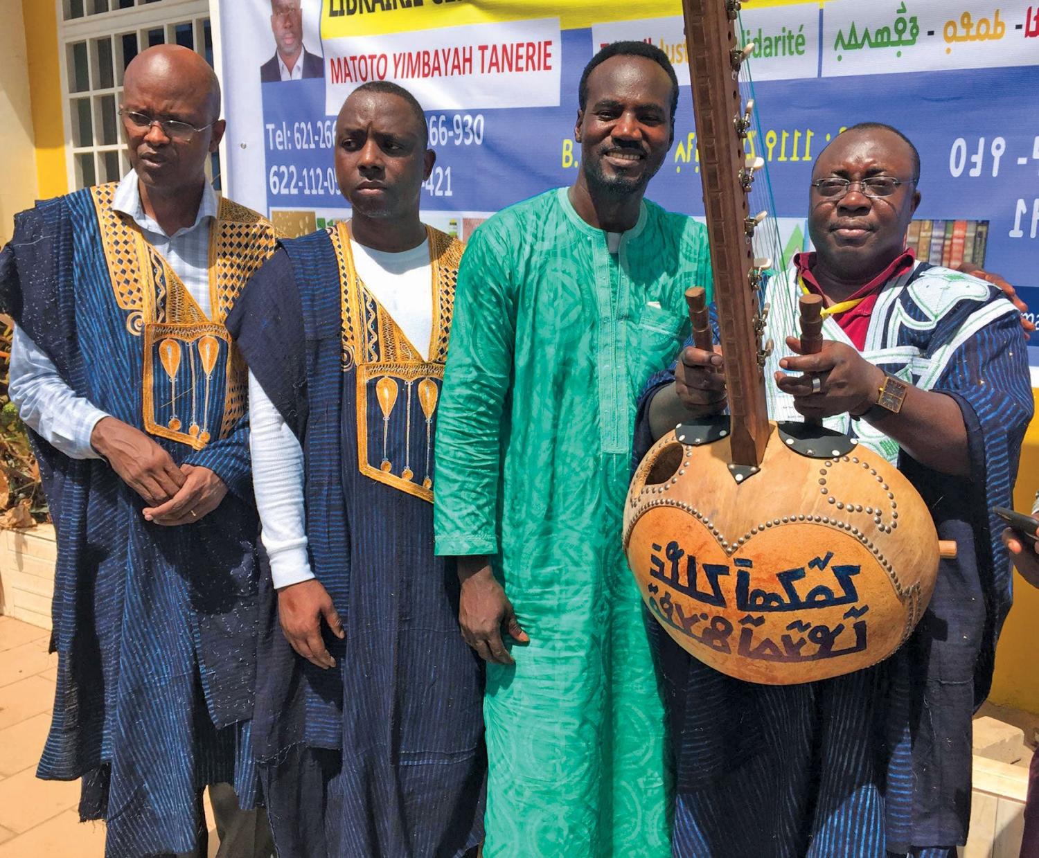 Researcher and colleagues in African garb with musical instrument