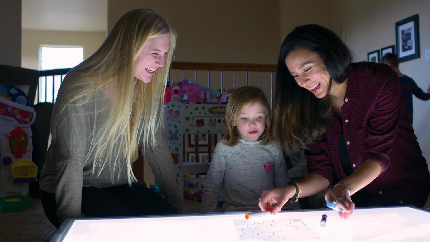 Researcher and children smiling at light table