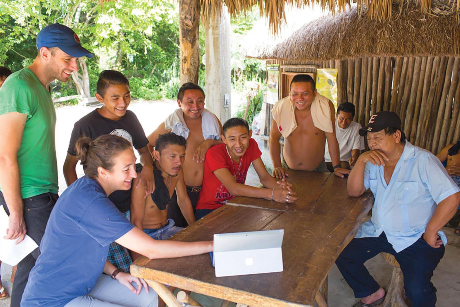 Researchers and locals smiling around a table outside