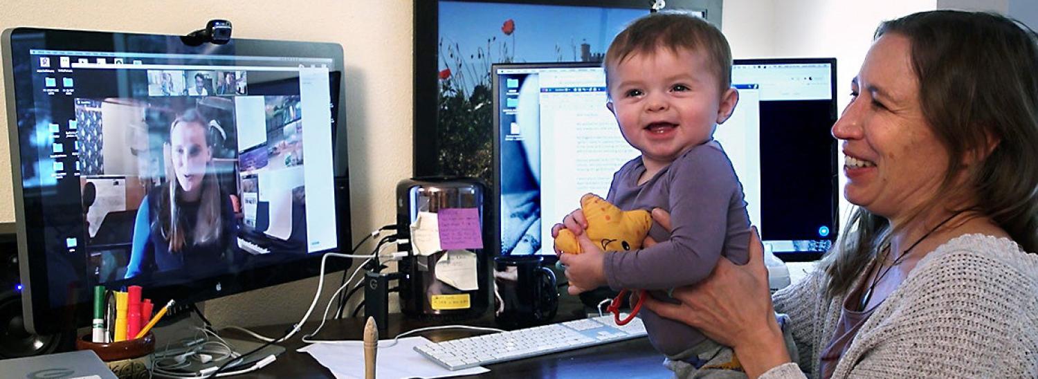 Mom holding baby with laptop in background