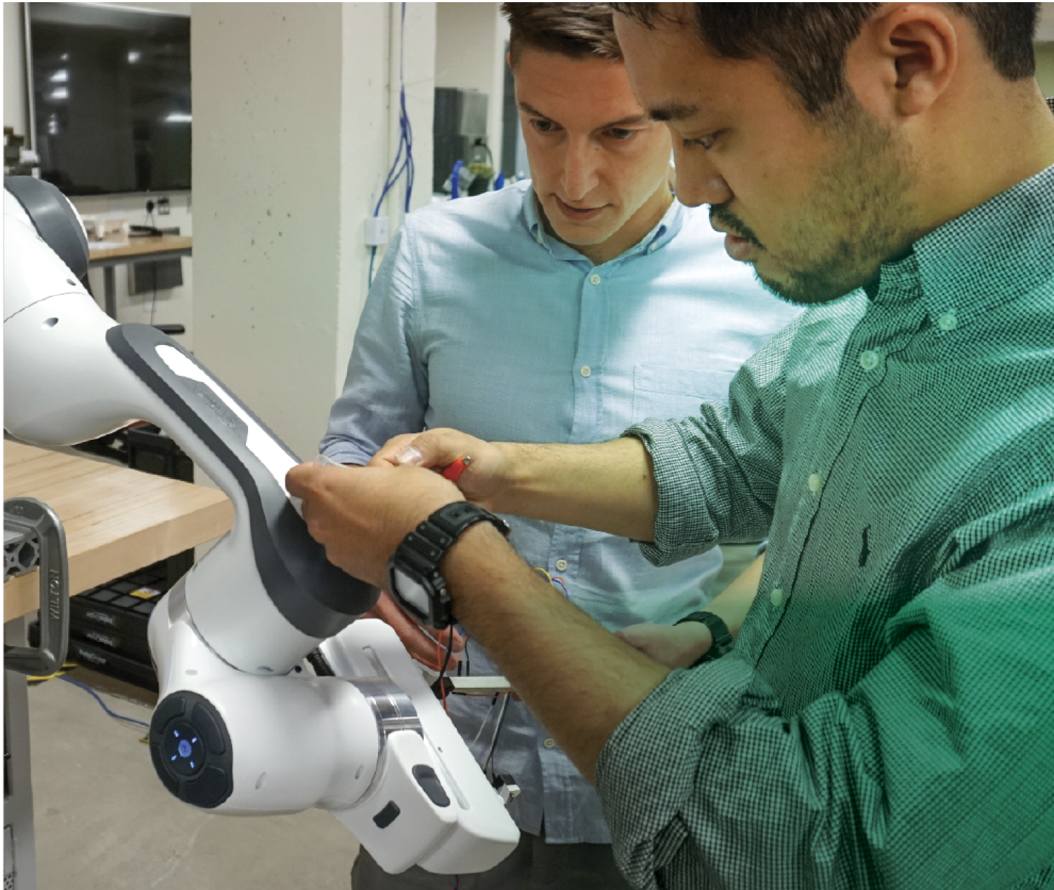 Alessandro Roncone and a PhD student work on a collaborative robot