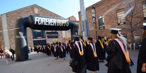 Procession of graduates through Forever Buffs archway