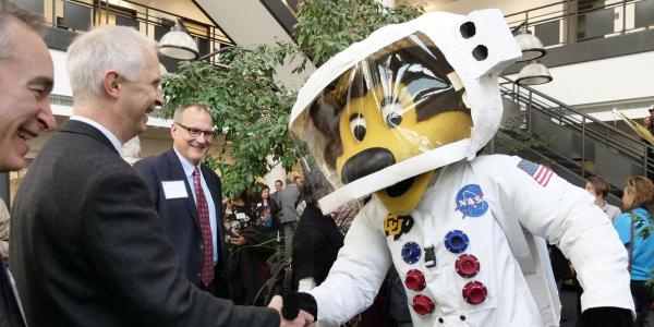 Ralphie mascot in an astronaut suit shaking hands