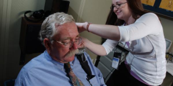 Women testing hearing aid of man