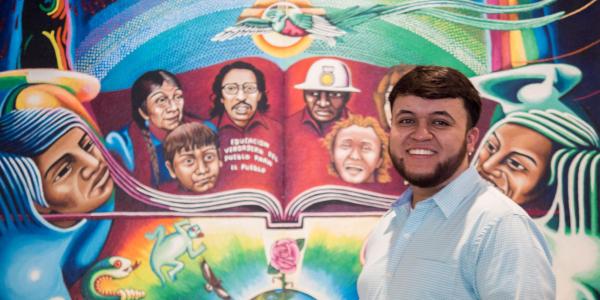 Student in front of colorful mural
