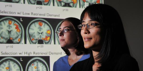 Two women next to screen showing the human brain