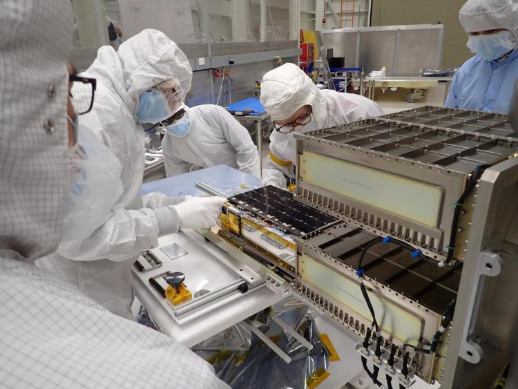 Graduate students and LASP engineer Nicholas DeCicco install CUTE into LANDSAT-9