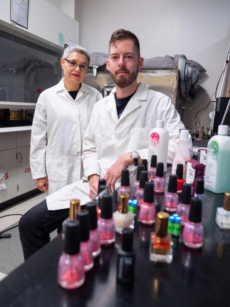 CU Boulder Professor Lupita Montoya and undergraduate student standing behind bottles of nail polish