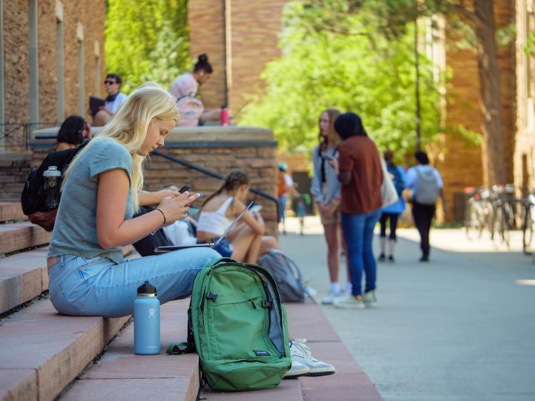 Student sitting on campus steps and looking at her phone
